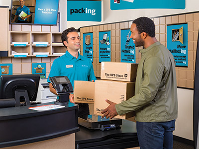 Shipping services Associate holding door for customer with boxes